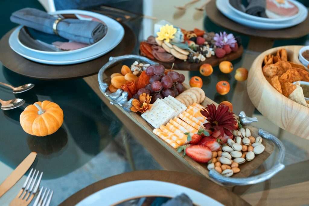 Elegant charcuterie board featuring cheeses, fruits, and nuts on a fall-themed table setting.